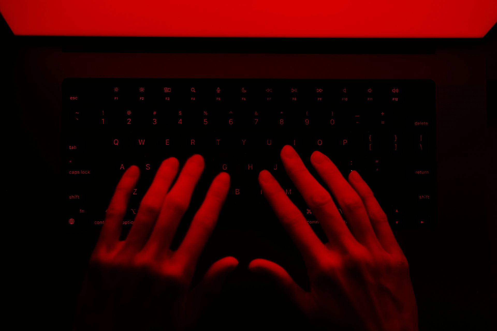 hands on a keyboard under red lighting