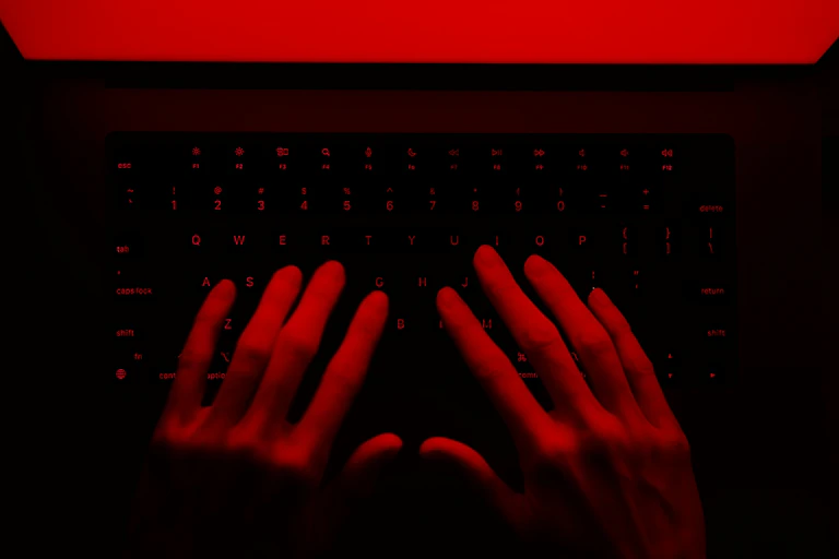 hands on a keyboard under red lighting