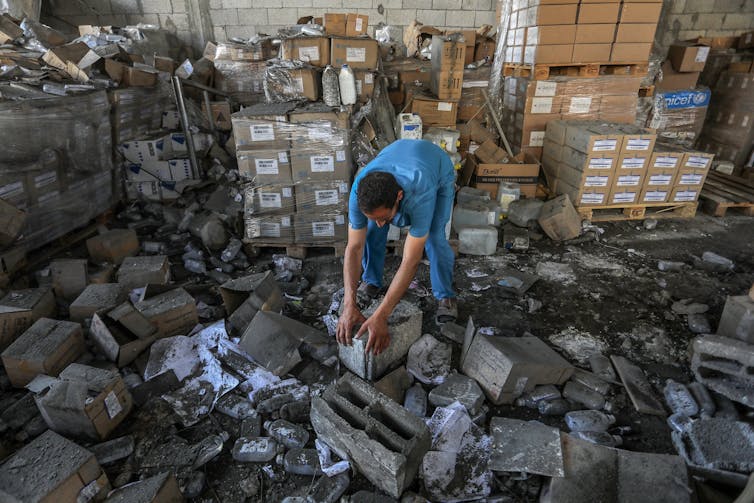 A Palestinian hospital worker inspects damage to a bombed warehouse.