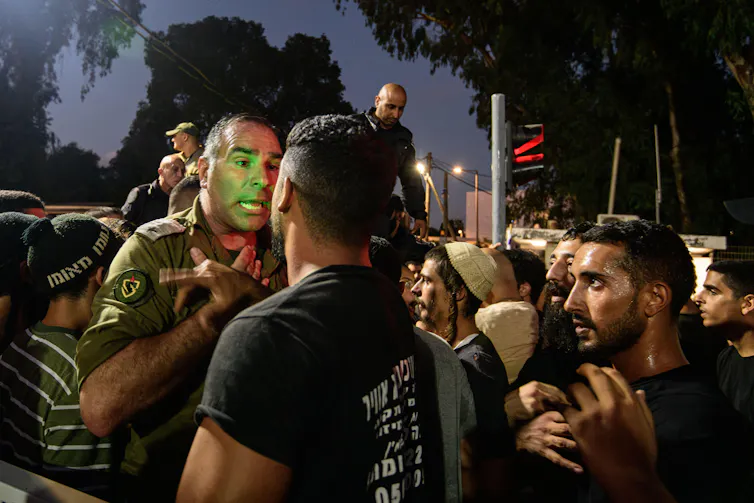 An army officer speaks with Israeli activists during a protest.