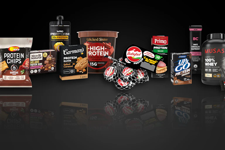 A row of black packaged protein products with a black background and a reflection at the bottom
