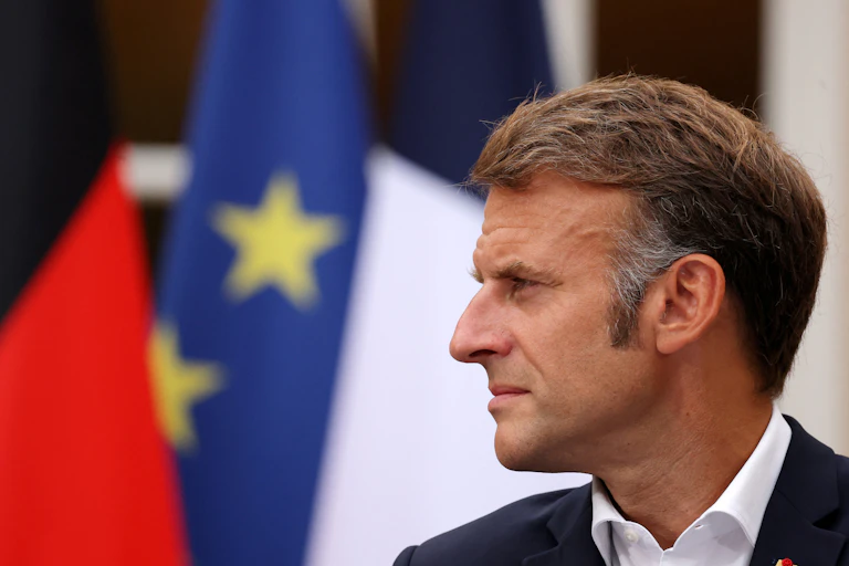 Man in suit looks pensive with several flags in the background