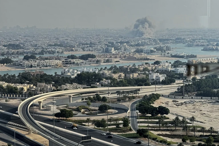 Aerial view of Doha with smoke rising from a blast site