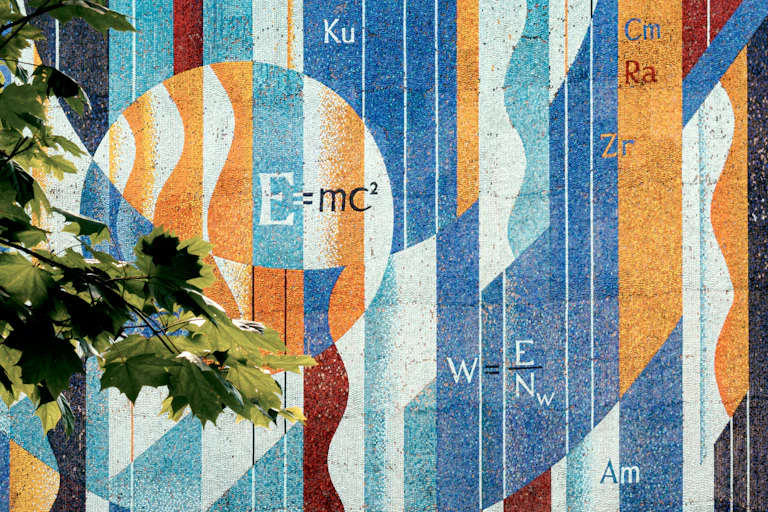 A colourful mosaic wall with physics equations and chemical elements in an artistic layout.