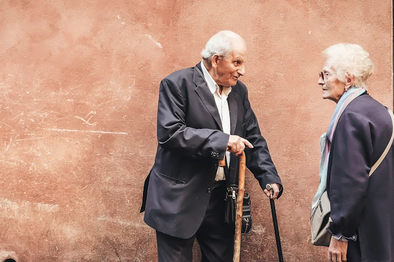 An older man and woman speaking on a city street