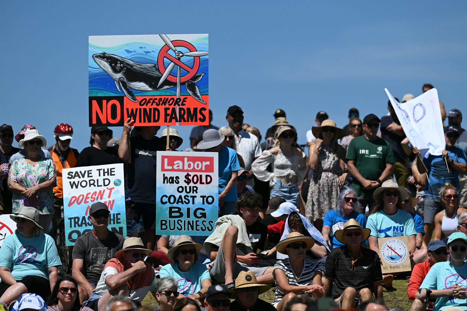 People hold up signs opposing an offshore wind farm.
