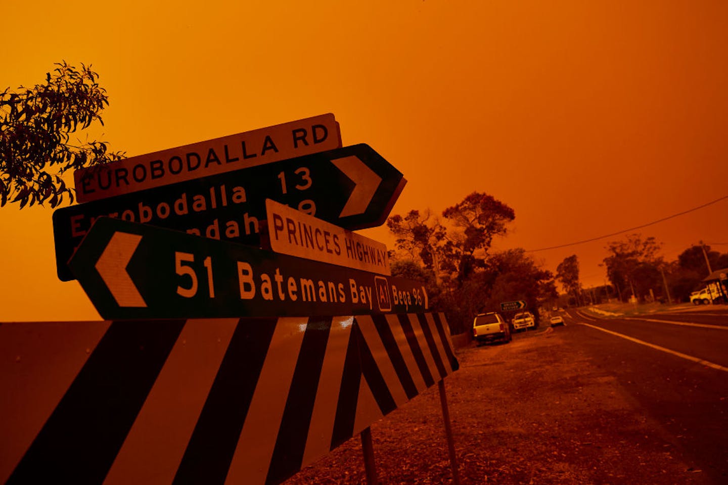 Signs pointing to various towns amid an orange haze
