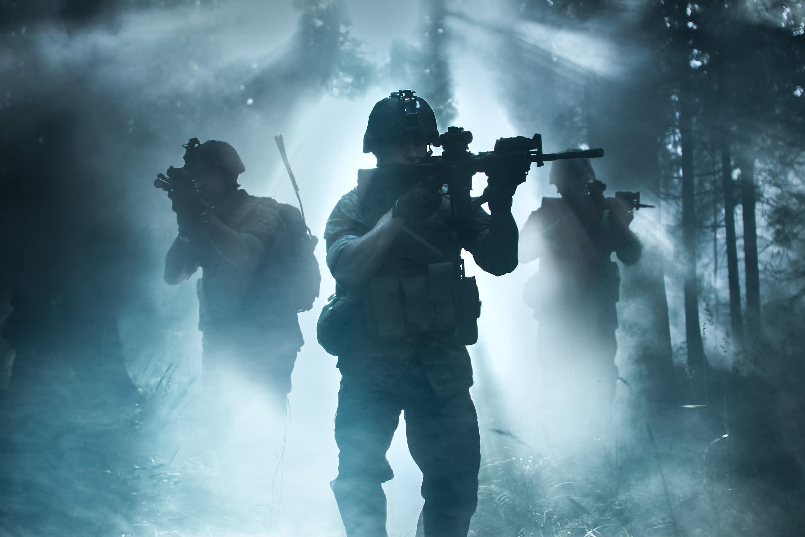 Silhouettes of three soldiers moving through a forest.