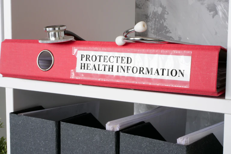 A red binder labeled "protected health information" with a stethoscope on it