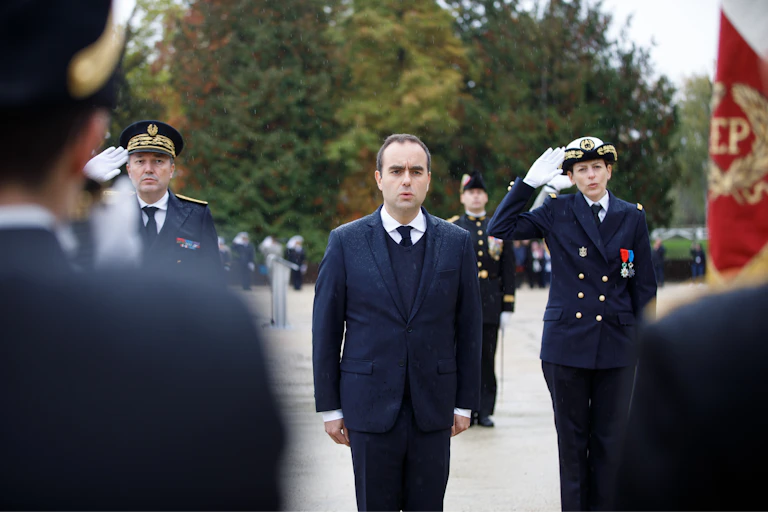 Un hombre trajeado flanqueado por dos militares durante una ceremonia militar