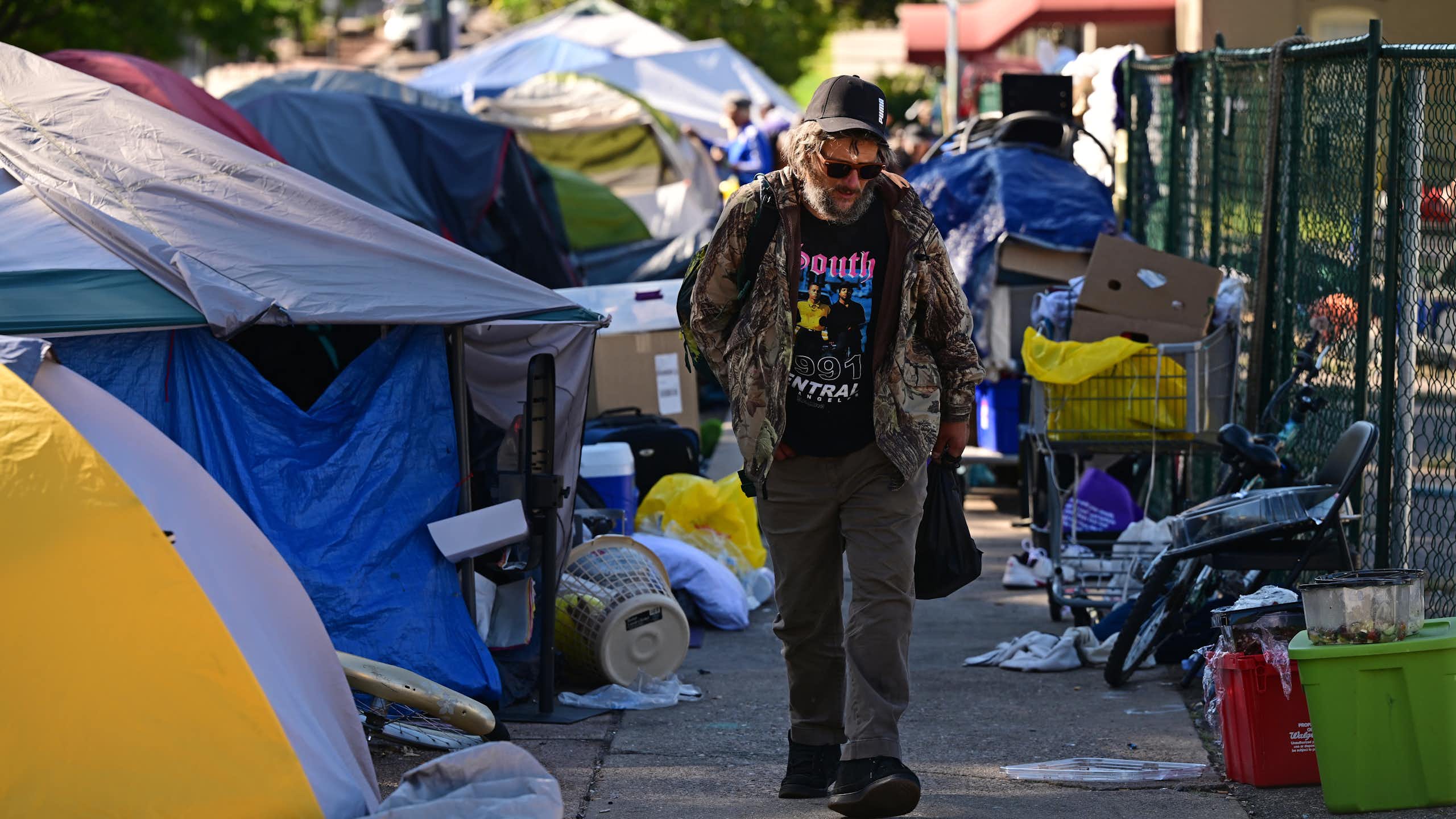 A man walks down a street filled with tents.