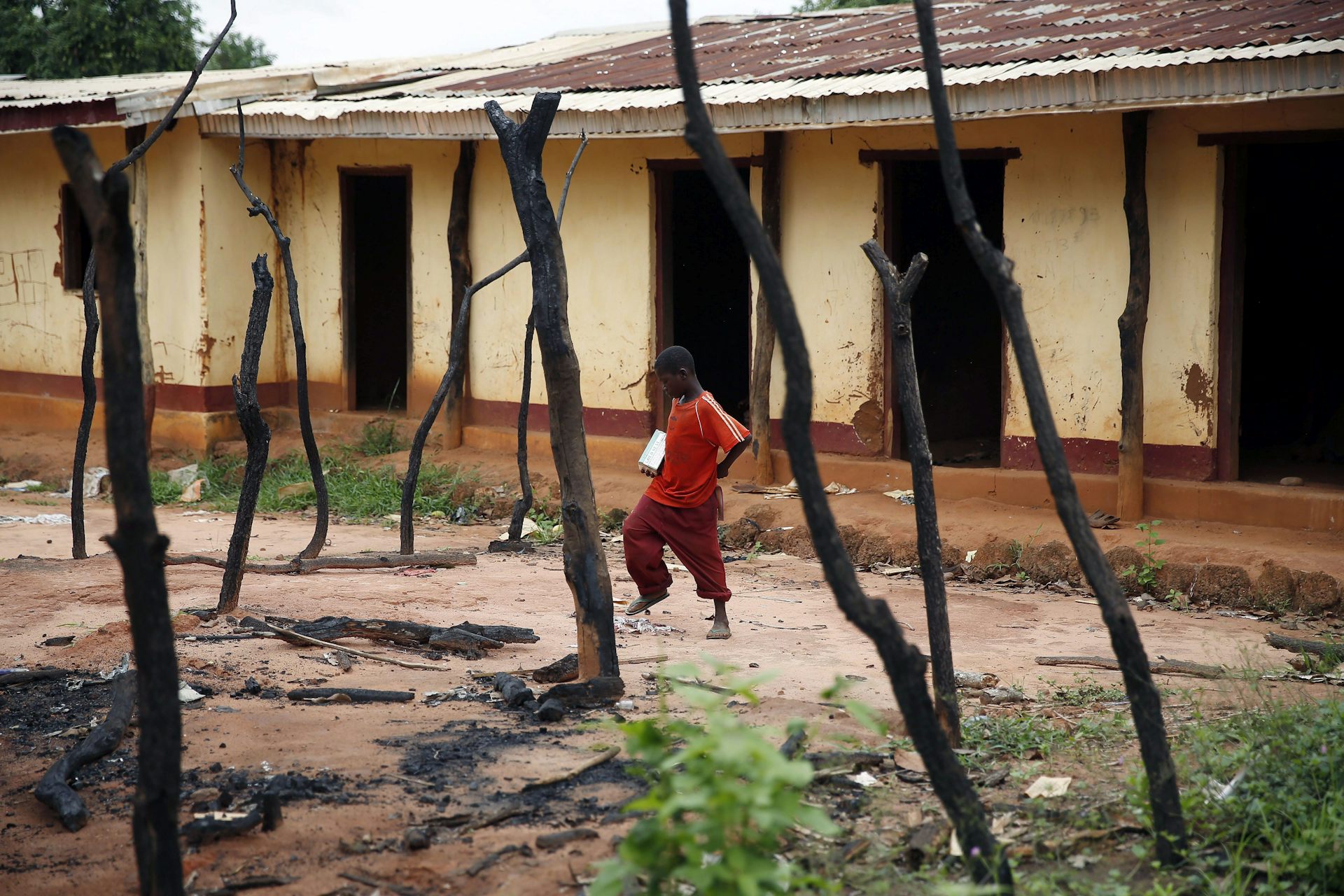 a young boy walks past a burned-out storefront