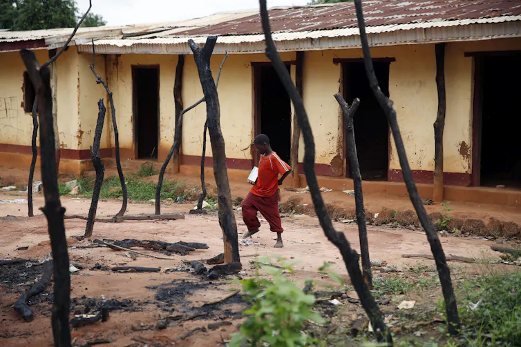 a young boy walks past a burned-out storefront