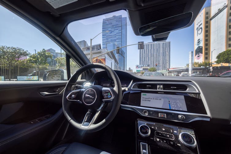 a taxi driving with no driver, no one at steering wheel. photo from inside the car looking out.