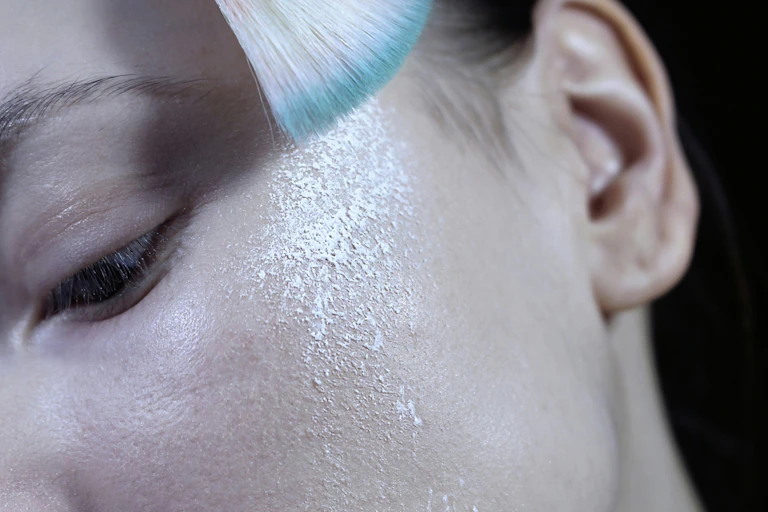 A woman with white powder sprinkled on her cheekbone.