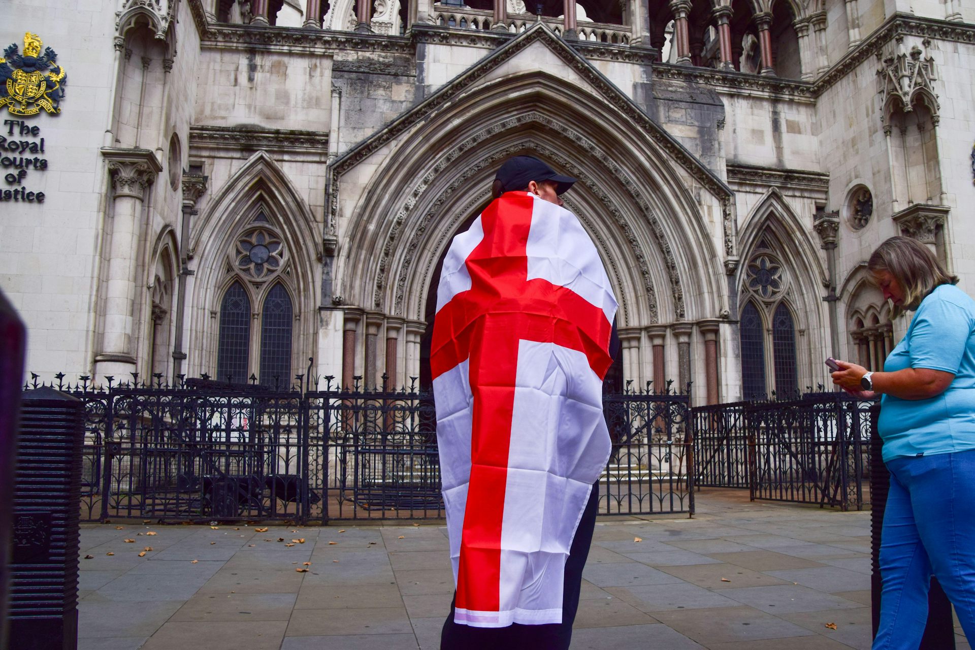 A man wrapped in an English flag standing outside the Royal Courts of Justice in London.
