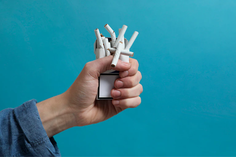 Una mano estruja una cajetilla de cigarrillos