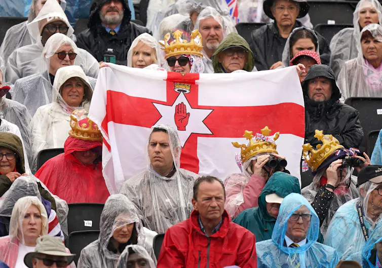 A woman holding up and Ulster Banner flag.