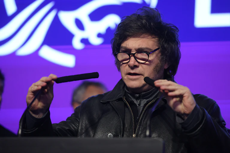 argentine president javier milei standing in front of microphones after his party's election defeat.