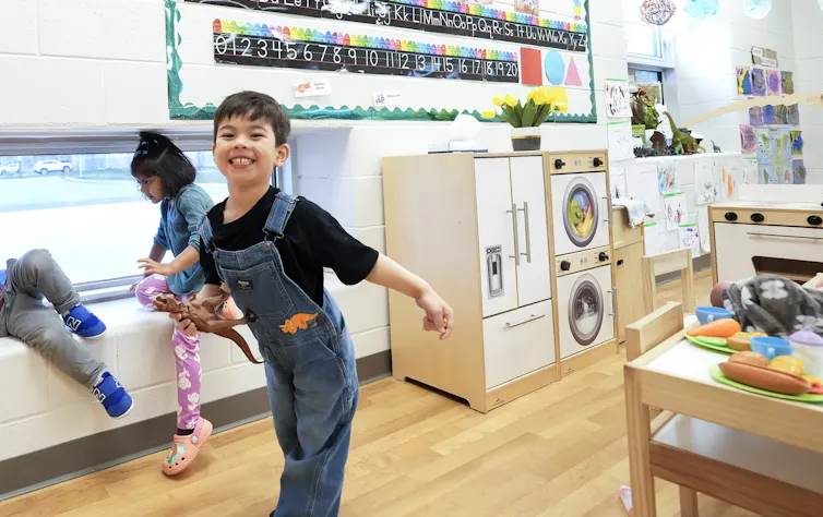 A child swinging his arms and smiling.