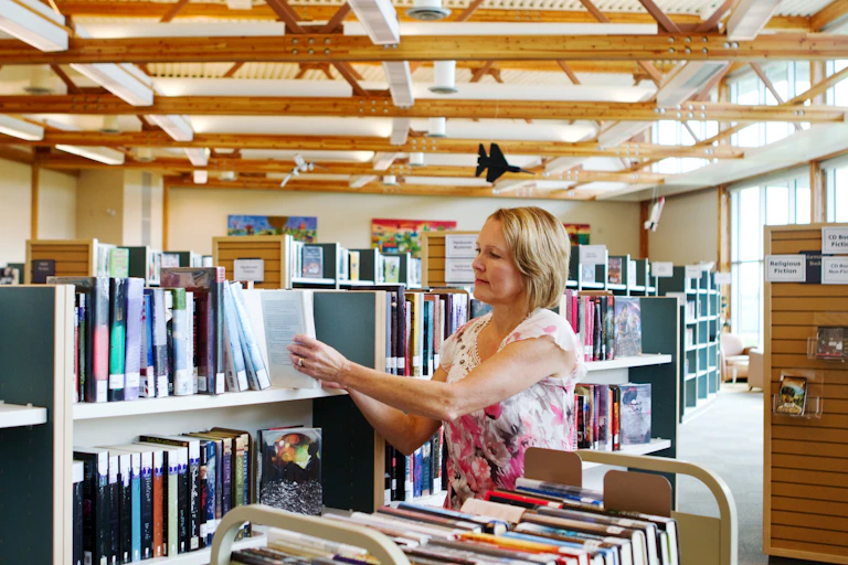 Librarian with a book cart restocking shelves in a school library