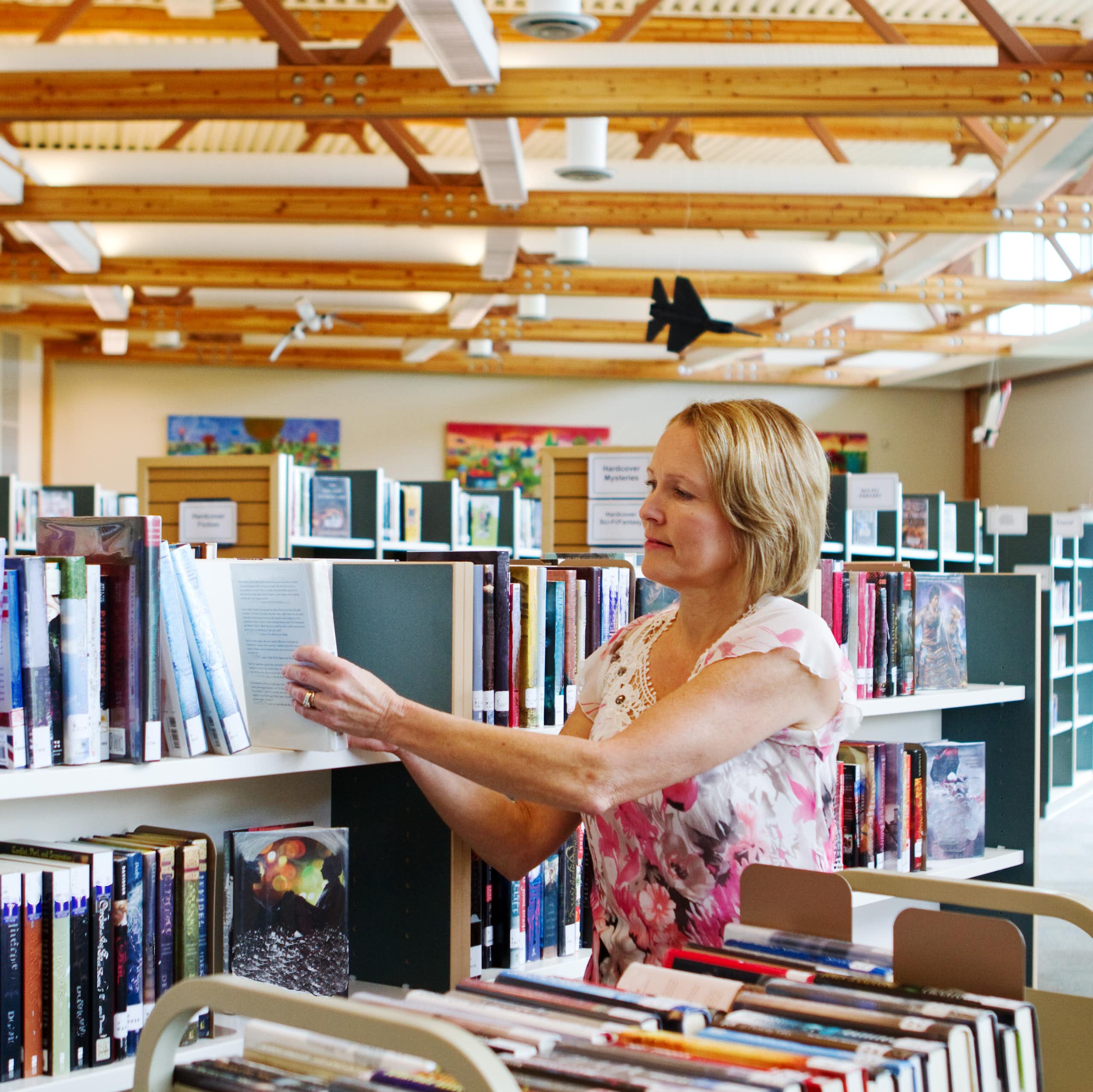 Librarian with a book cart restocking shelves in a school library