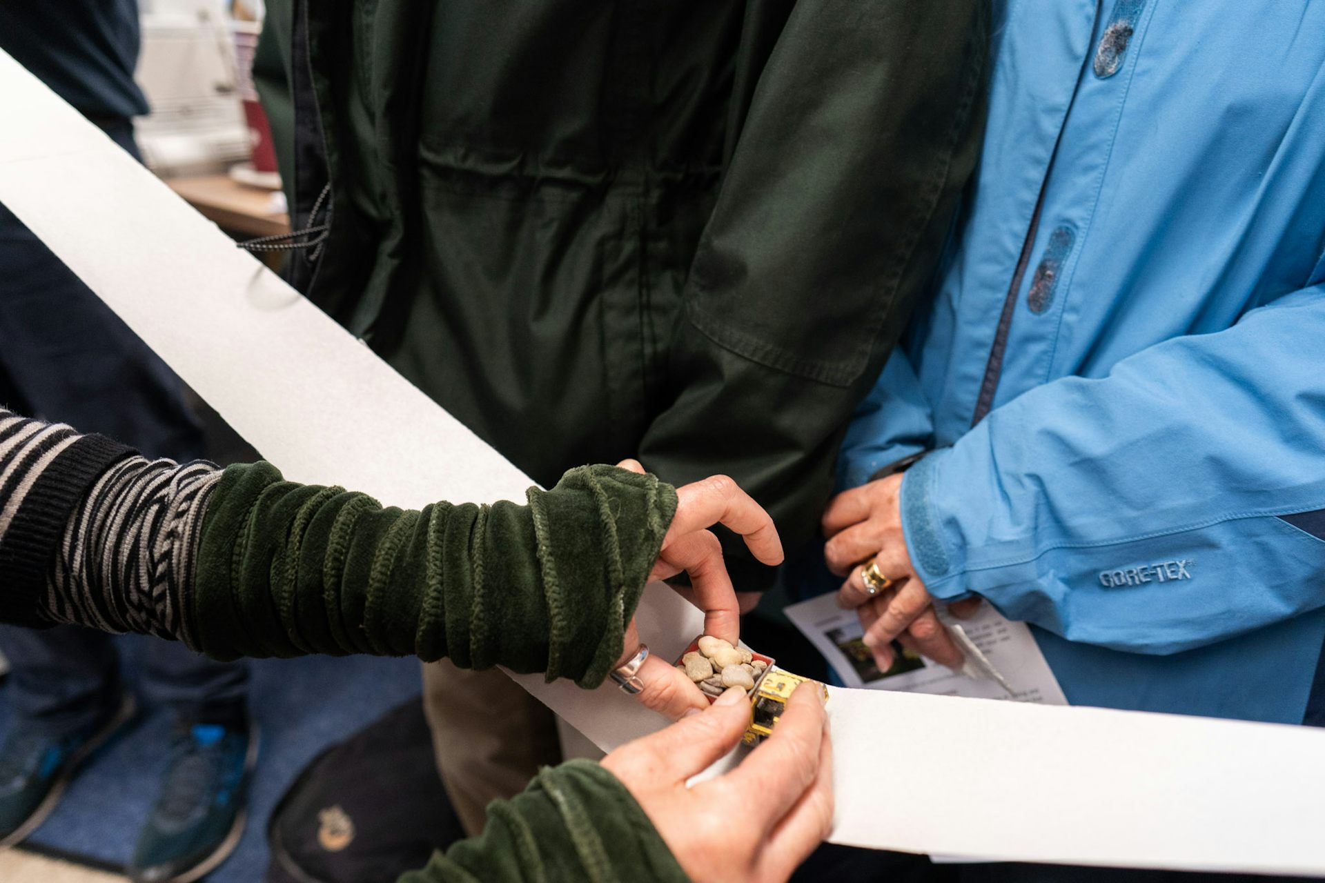 A close up of people's hands with a small toy lorry in the middle.