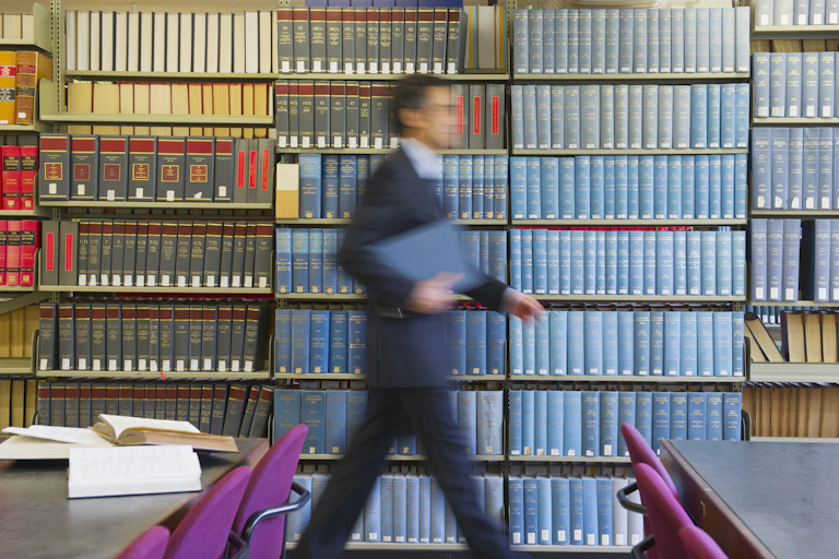 blurred man in suit walks by shelves of colorful journals