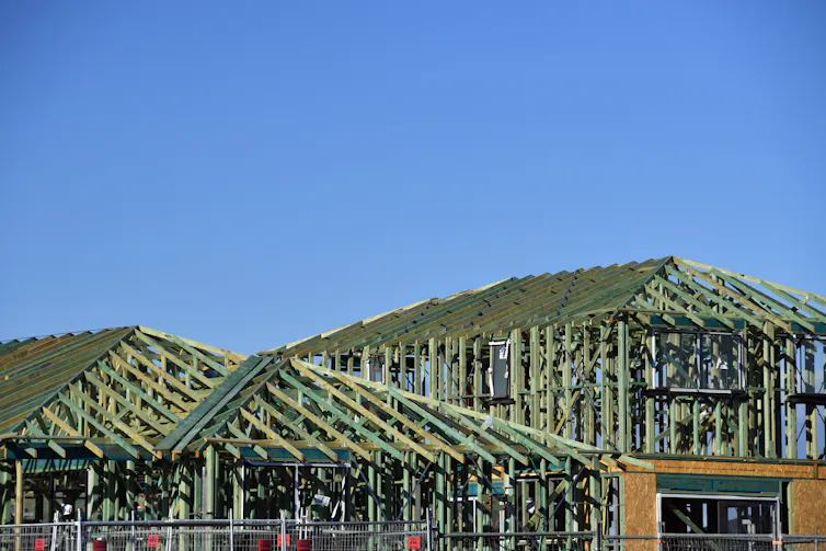 A half-constructed house with blue wooden beams.