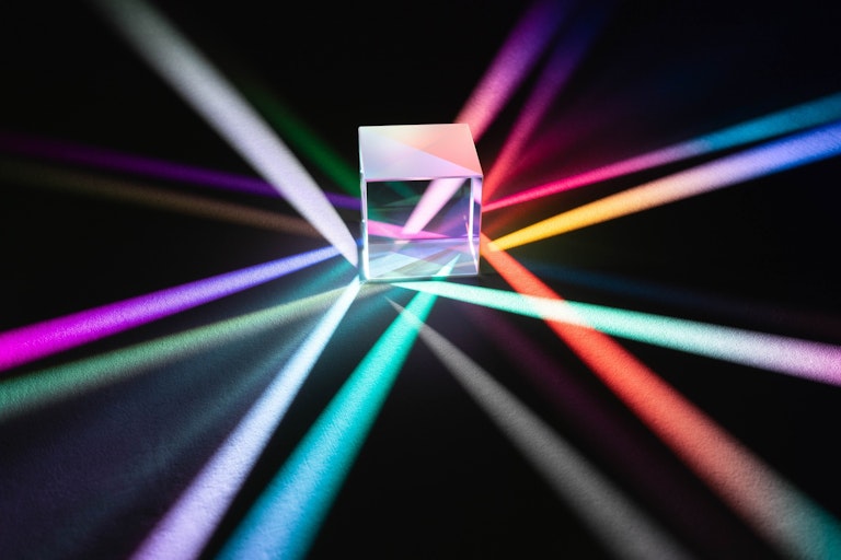 A glass cube refracting beams of coloured light