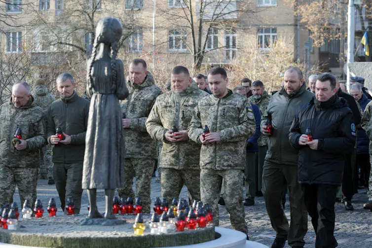 Soldiers stand before a memorial.