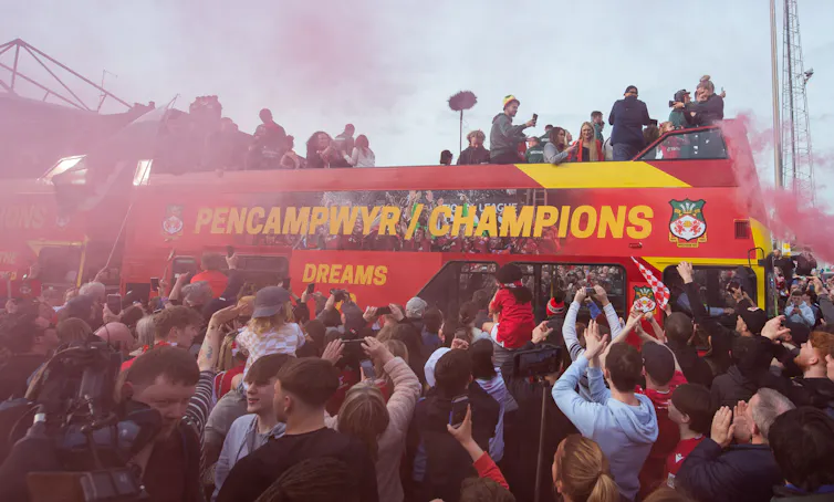 Open top 'champions' bus surrounded by fans.
