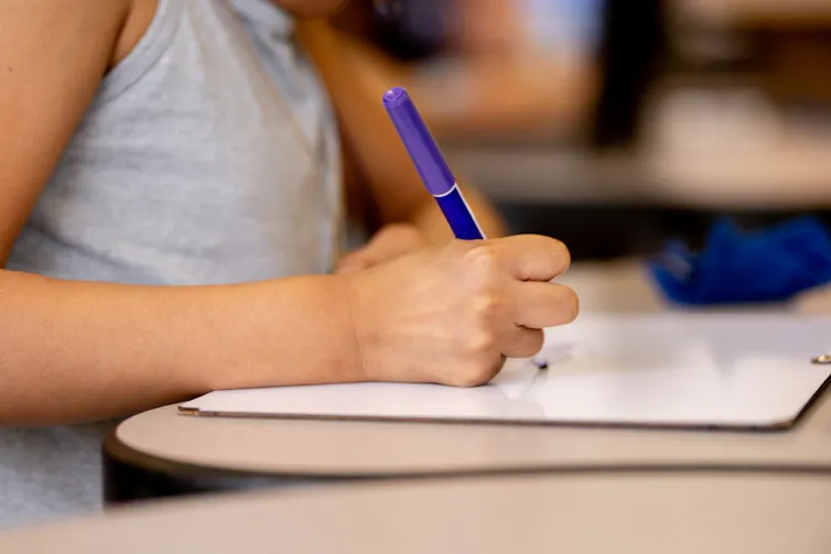 Une fille écrivant sur un cahier avec un stylo