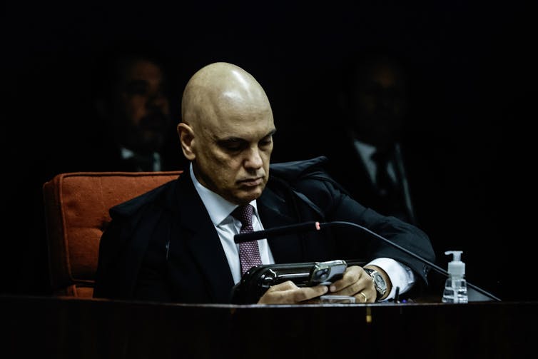 Alexandre de Moraes sat at a desk on his phone.