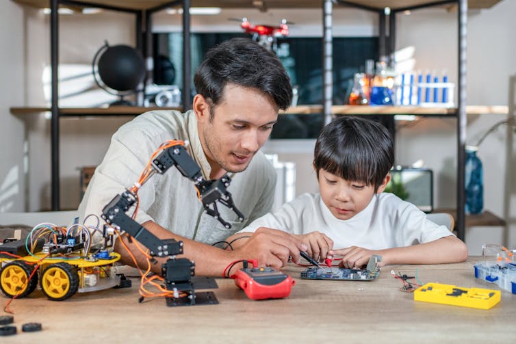 man and boy working with tools on a robot toy