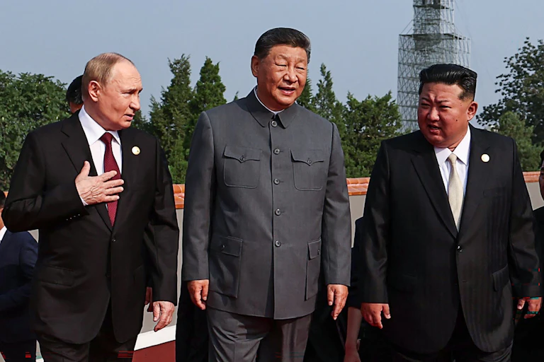 Three men in suits stand next to each other.