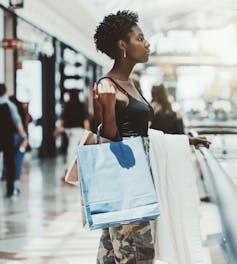 La mujer está en el centro comercial que compra dos bolsas para salir de la mano.