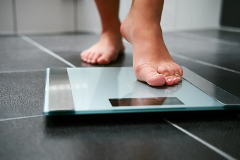 Person stepping on a bathroom scale.