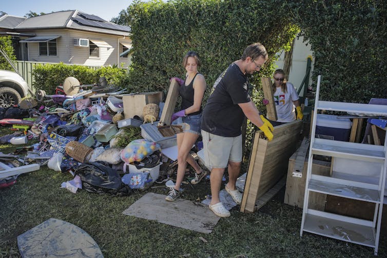 A man and his daughter carry debris to a pile