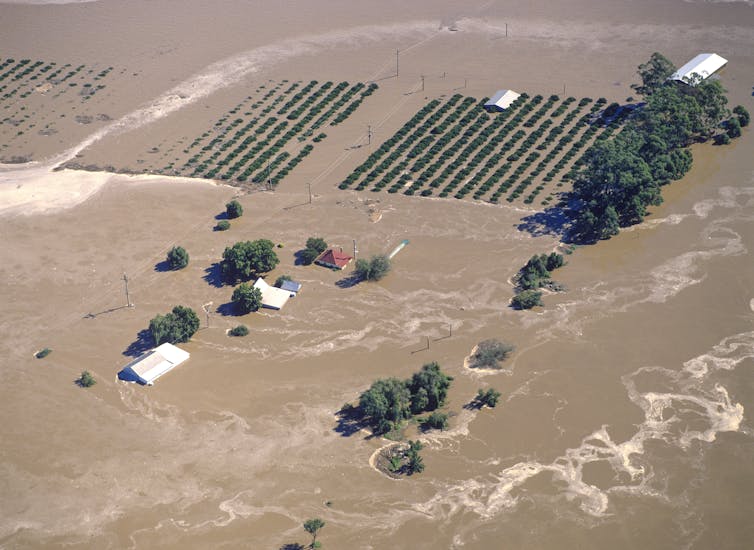 aerial shot of a flooded farm, crops and farmhouse under water.