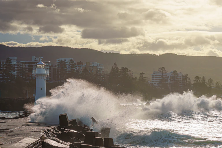waves washing over a seawall, landscape shot, a small lighthouse in foreground