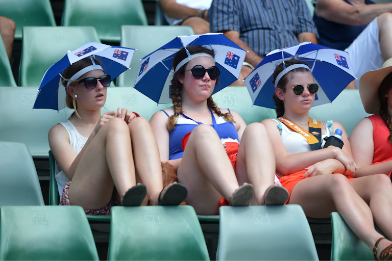 Three girls sitting under umbrellas