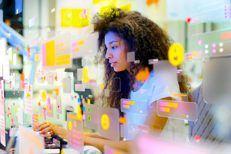 A young woman types. The images is overlaid with apps, screens and symbols.