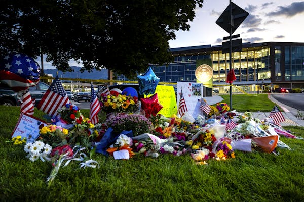 Brightly colored flowers, flags and balloons lying on the grass in front of a building.