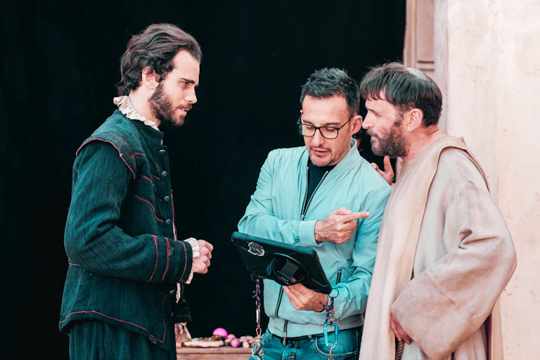Un hombre da instrucciones a dos vestidos de época.