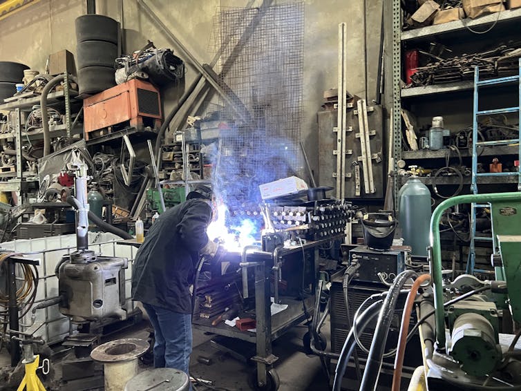 A woman works at a welding table.