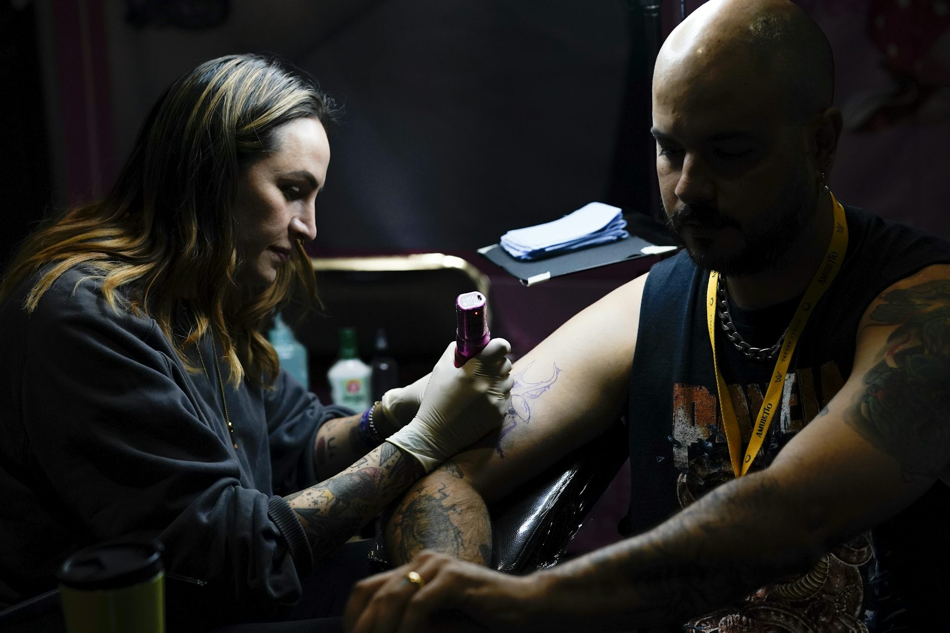 A woman tattoos a man's upper arm