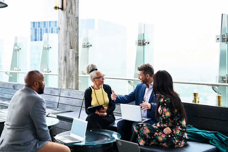 A group of diverse colleagues sitting with laptops and discussing