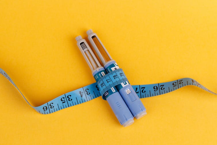 Two vials of semaglutide, with a blue measuring tape wrapped around them.