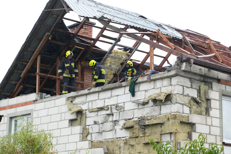 Firefighters on a destroyed roof of a house.